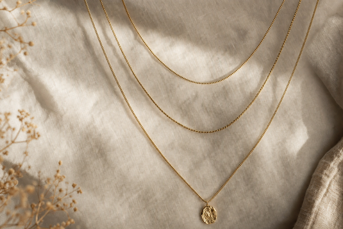 Three layered gold chain necklaces on linen