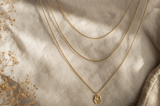 Three layered gold chain necklaces on linen