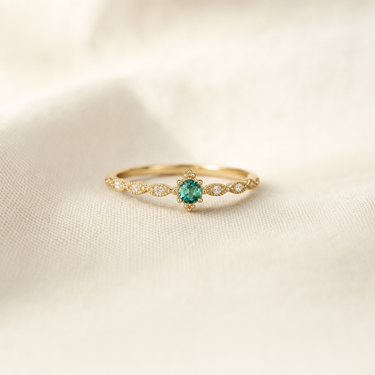 Gold ring with round teal gemstone and milgrain detail on linen